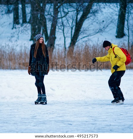 Young girl and fellow ice skating in the winter rink covered with snow in Trakai in Lithuania.