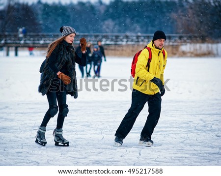 Girl and fellow ice skating in the winter rink covered with snow in Trakai, Lithuania.