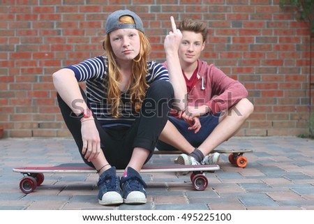 Portrait of two cool young teenagers outdoors with their skateboards