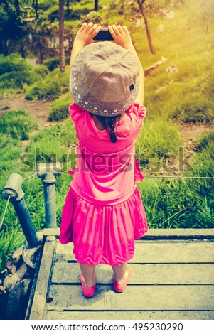 Back view of asian girl with camera at national park . Child relaxing outdoors with bright sunlight at the day time, travel on vacation. Cross process and vintage tone effect.