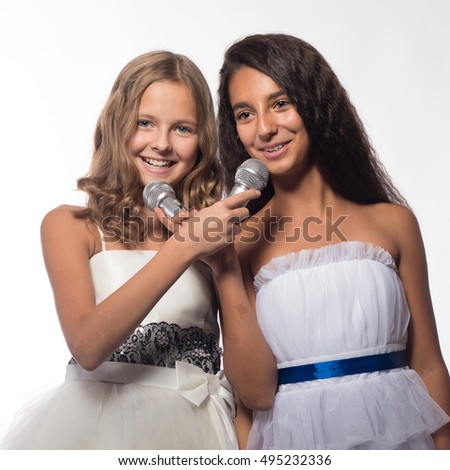 Two girls blonde and brunette in a white dress with a microphone on a white background