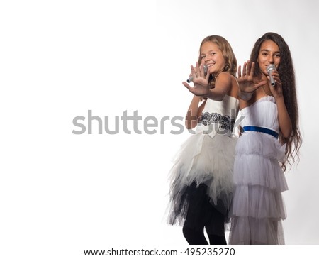 Two girls blonde and brunette in a white dress with a microphone on a white background