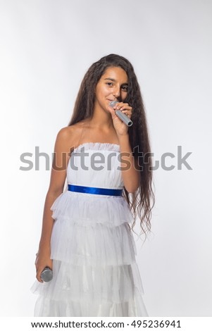 Girl brunette in a white dress with a microphone on a white background