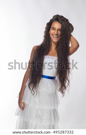 Emotional young brunette girl with long hair in a white dress on a white background