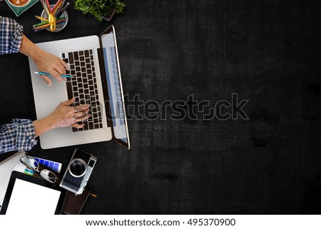 Man working with laptop over Work space rustic wood table. Top view shot