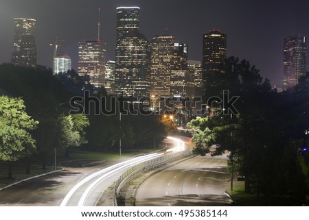 Long-exposure of cars racing over a freeway in downtown Houston, Texas with the Houston skyline in the background at night