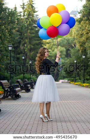 Girl with colorful balloons walking in park