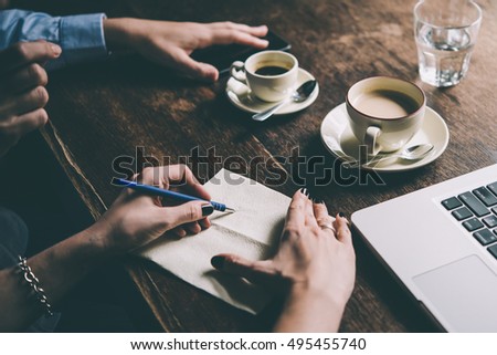 Two women discussing business projects in a cafe while having coffee. Startup, ideas and brain storm concept. Toned picture