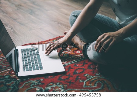 Woman works with laptop on the vintage carpet on the floor. Toned picture