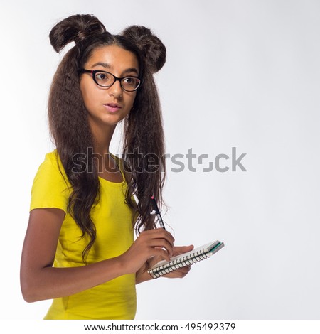 Emotional young brunette girl with long hair in yellow t-shirt with a turquoise notebook and pen for notes on a white background