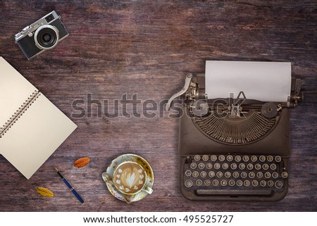 Vintage typewriter, camera and a cup of coffee on wood background