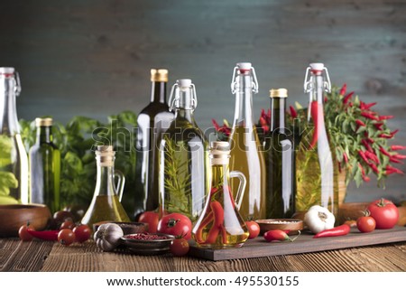 Olive oil and rosemary, chili pepper, many different tomatoes, garlic,
red, white, green pepper on old wooden table. Extra virgin olive oil cruets and flavored olive oils with rosemary and chili. 