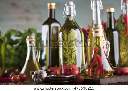 Olive oil and rosemary, chili pepper, many different tomatoes, garlic,
red, white, green pepper on old wooden table. Extra virgin olive oil cruets and flavored olive oils with rosemary and chili. 