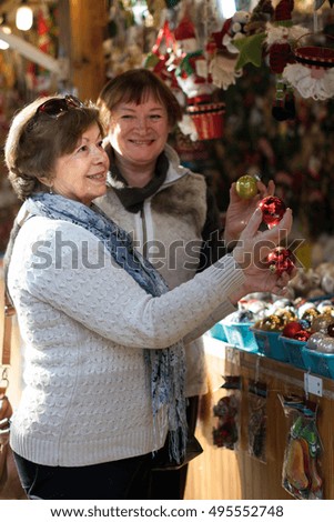 Cheerful female pensioners buying Christmas decorations at fair
