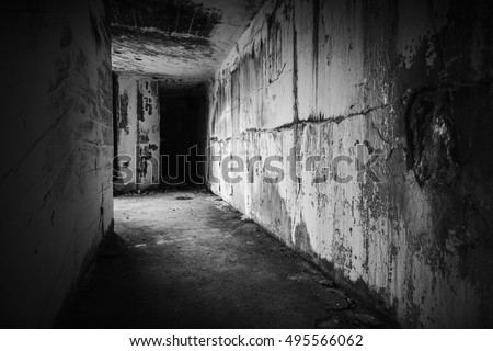 Empty abandoned bunker interior with dark end of grungy corridor, black and white photo