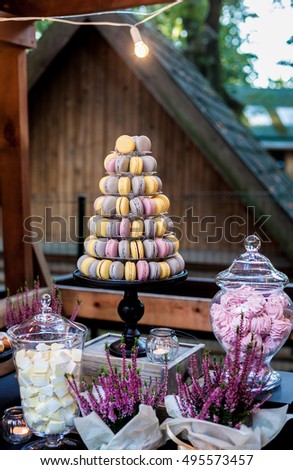 Colorful macarons on pyramid-shaped plastic tower stand as part of candy bar sweet table