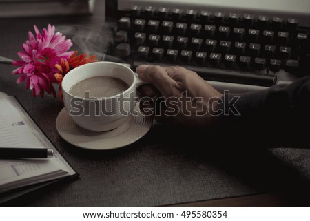 Vintage typewriter and coffee on stone board.
Hand holder coffee cup.