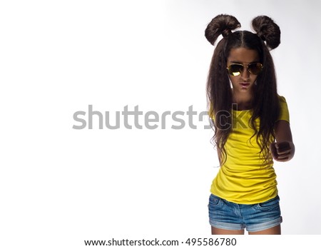 Emotional young brunette girl with long hair in yellow shirt and sunglasses on a white background