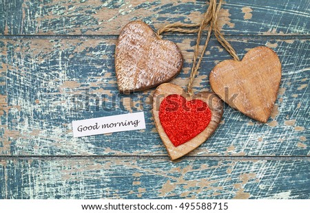 Good morning card with three wooden hearts on rustic surface
