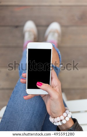 Close up of women's hands holding cell telephone with blank copy space screen for your advertising text message or promotional content, hipster girl watching video on mobile phone during coffee break Royalty-Free Stock Photo #495591280