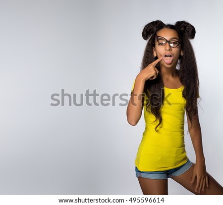 Emotional young brunette girl with long hair in yellow shirt and glasses on a white background