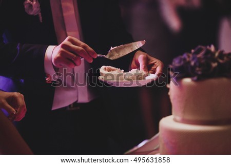 Groom holds in his hands a plate with white wedding cake