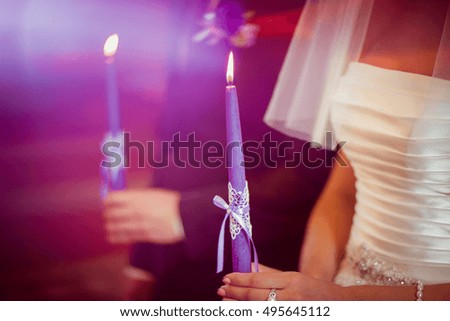 The beautiful brides keep  candles in church