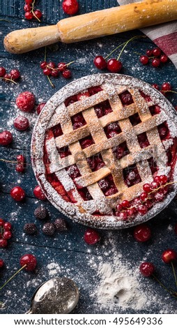 Berry pie decorated with sugar powder and rocker on the navy-blue background