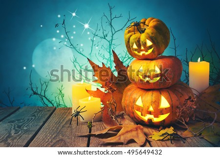 Halloween background with pumpkin jack o lantern on wooden table over spooky trees