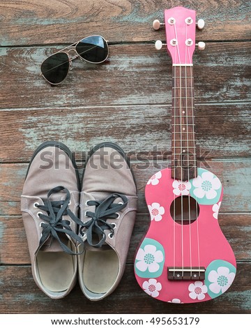 colorful ukulele with sunglasses and shoes on vintage wood background