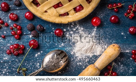 Berry pie decorated with sugar powder, berry and rocker on the navy blue background