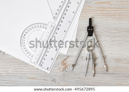 Layout with compass, protractor and centimeter ruler on wooden surface in top view. Workplace of draftsman, architect, constructor or designer. Engineering work. Measurement. Tools for drawing.