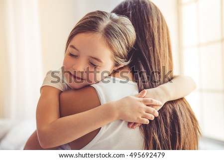 Beautiful young woman and her charming little daughter are hugging and smiling Royalty-Free Stock Photo #495692479