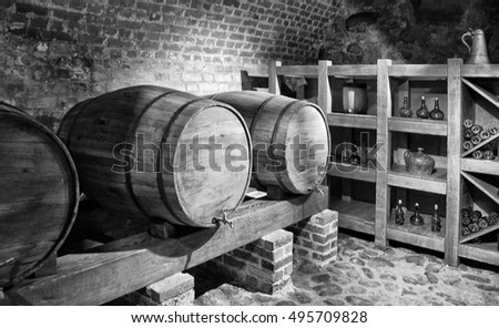 Barrels with a wine in a cellar with a brick wall background. Black and White Photography. Beautiful vintage.