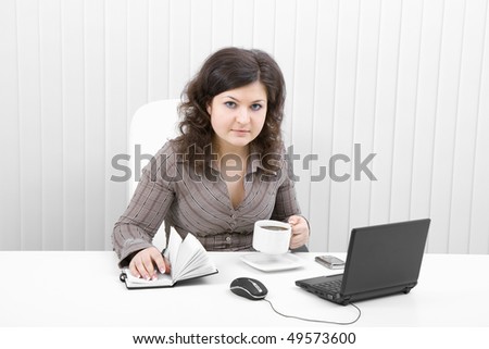The young brunette at office with the laptop and coffee