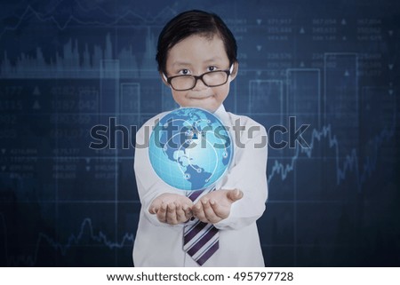 Little businessman wearing glasses and holding a globe with social network icon and financial statistic background. Elements of this image furnished by NASA