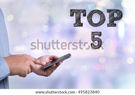 TOP 5 person holding a smartphone on blurred cityscape background