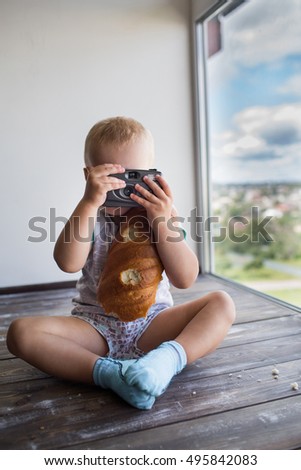 boy holding a camera. A child with bread in her hands. Baby learns to take pictures