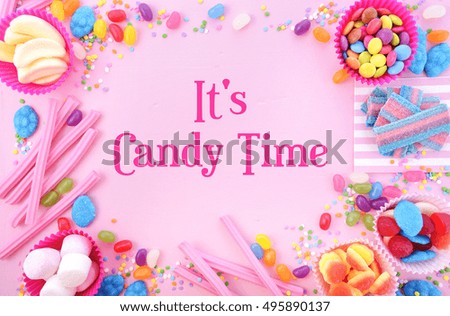 Background with decorated borders of bright colorful candy on pink wood table for Halloween trick of treat or childrens birthday party favors.