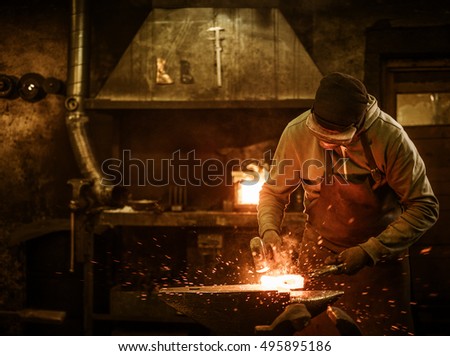 The blacksmith forging the molten metal on the anvil in smithy. Royalty-Free Stock Photo #495895186