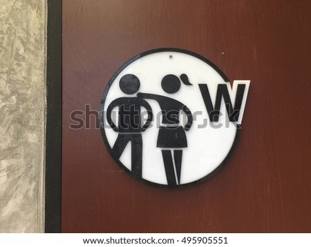 Symbols for restrooms man and woman with a circle style with black color with w alphabet on white background on the brown wooden door vintage style