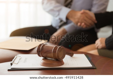 Judge gavel with legal documents and attorney hold hands client and give legal advice.