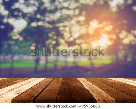 wood table and vintage tone blur image of forest on evening time for background usage.