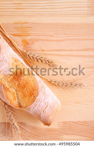 loaf of bread and wheat ears on a wooden background