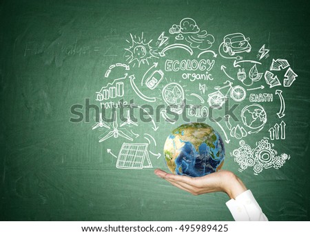 Close up of man's hand holding globe surrounded by sketches of renewable energy sources. Concept of being responsible. Mock up. Elements of this image furnished by NASA