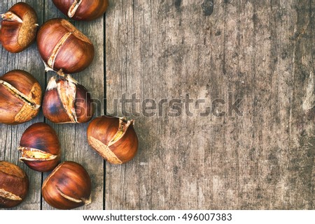 Roasted sweet chestnuts on grey rustic wooden table. Top view with plenty of copy space Royalty-Free Stock Photo #496007383