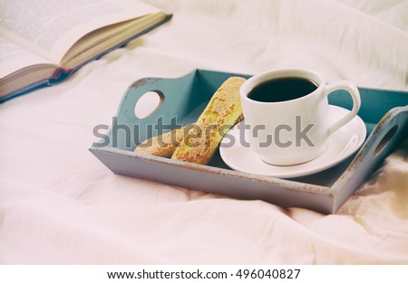 Image of romantic breakfast in the bed: cookies, hot coffee and open book