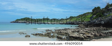 Beaches lined with rocks and bright sky with clouds.