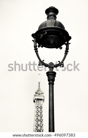 Parisian streetlight and Eiffel tower at background. Comparison concept. Black and white.