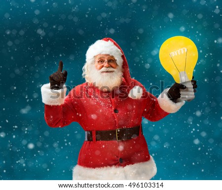 Emotional Santa Claus showing cartoon bulb - having good idea! Smiling Santa Claus on blue background. Merry Christmas & New Year's Eve concept.